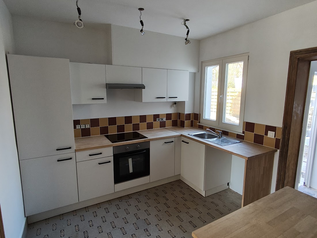 Une cuisine blanche avec des meubles modernes, des étagères et des appareils électroménagers.