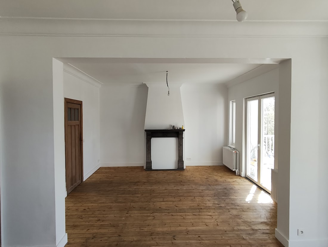 Un salon vide avec une cheminée et une porte en bois.