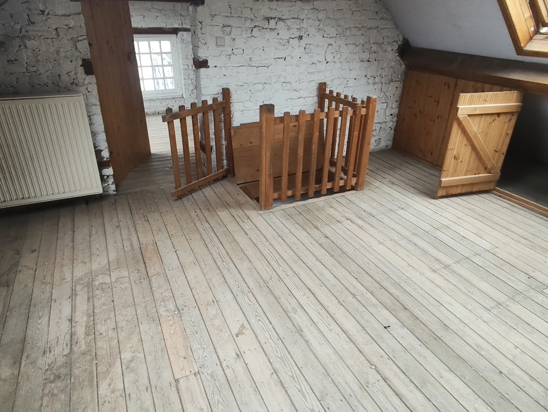 Une pièce de bois clair avec un sol en planches et un mur en brique blanche.